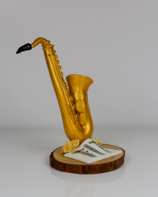 Gold saxophone figurine on a wooden base with a white card, against a light gray background