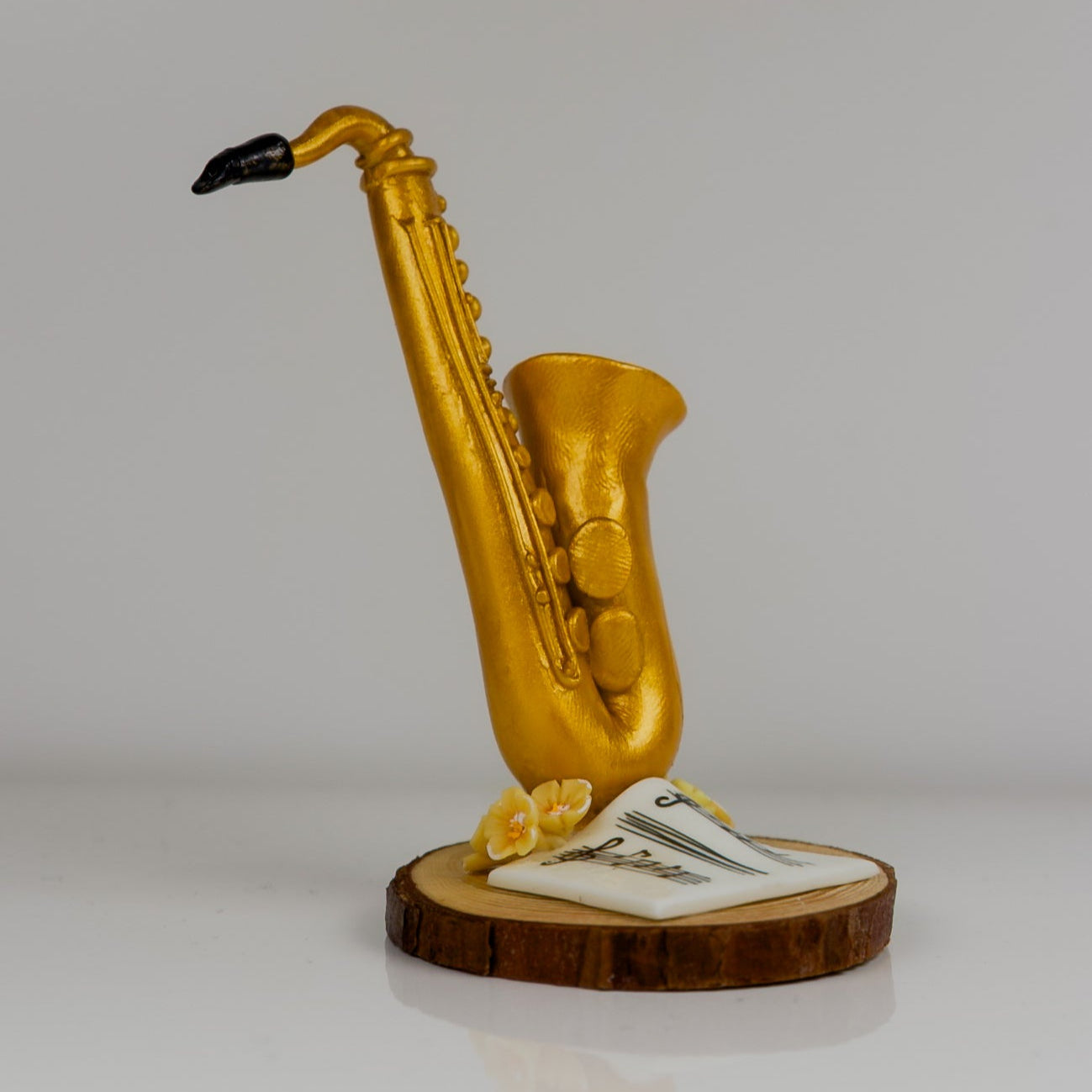 Gold saxophone sculpture on a wooden base with a gray background