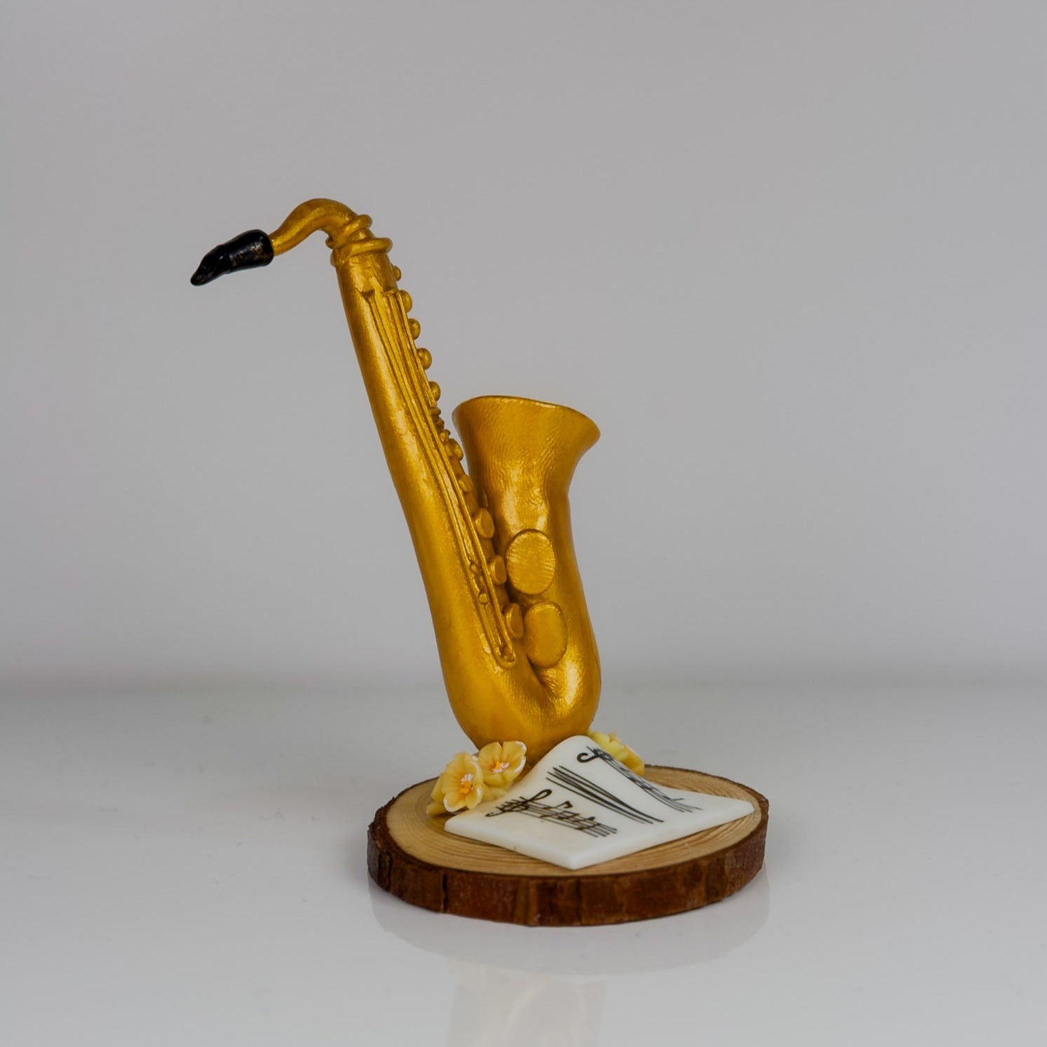 Gold saxophone figurine on a wooden base with a white card, against a light gray background