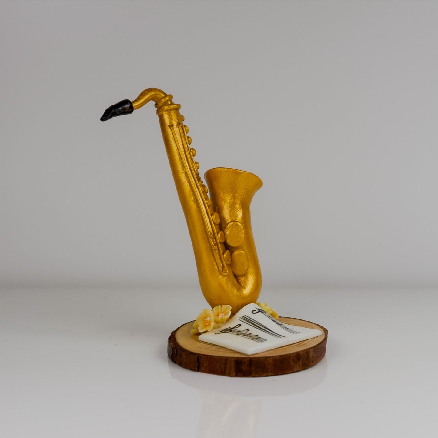 Gold saxophone figurine on a wooden base with a white card on a gray background