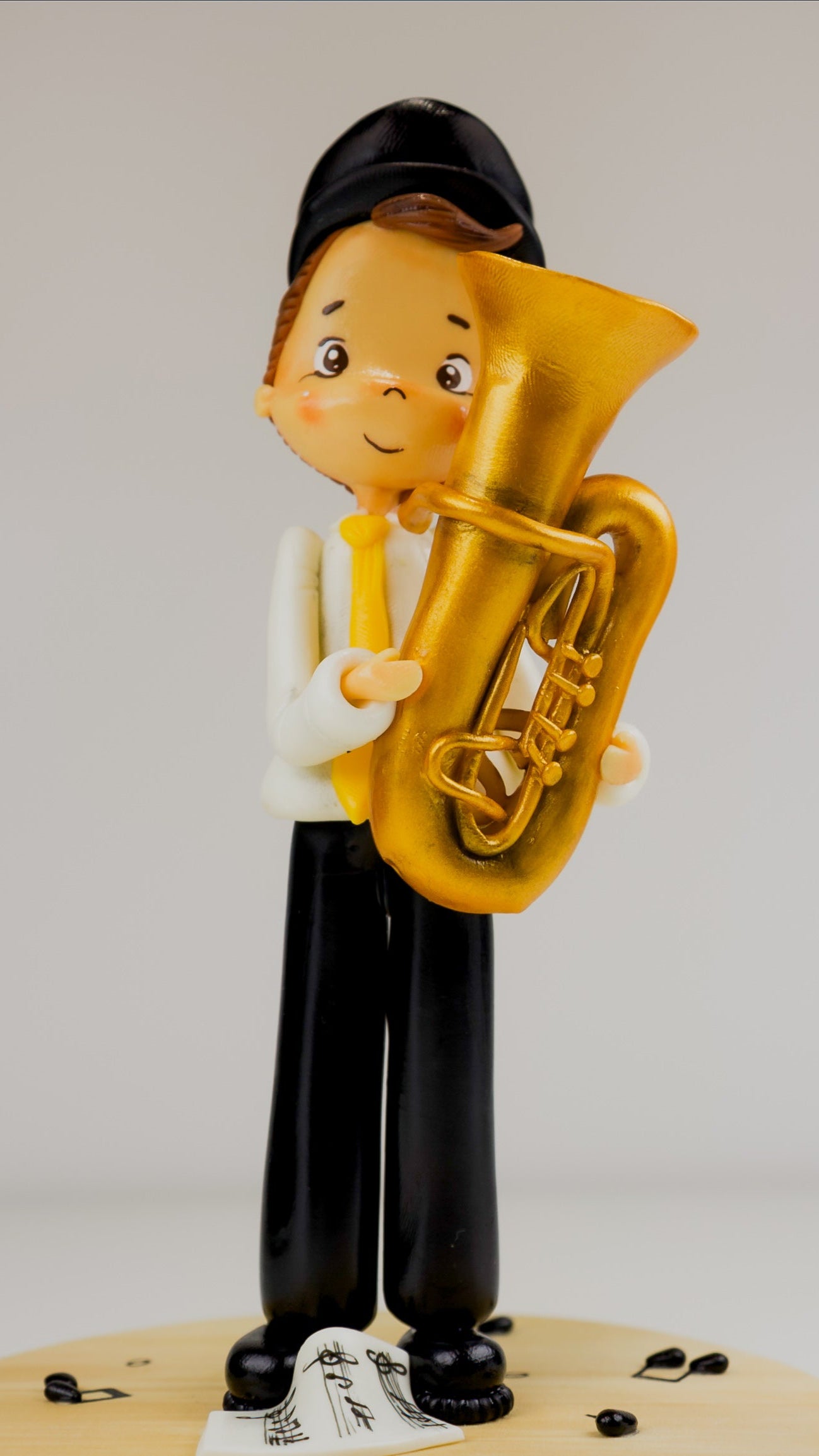 Figurine of a person playing a tuba on a wooden surface with a white background