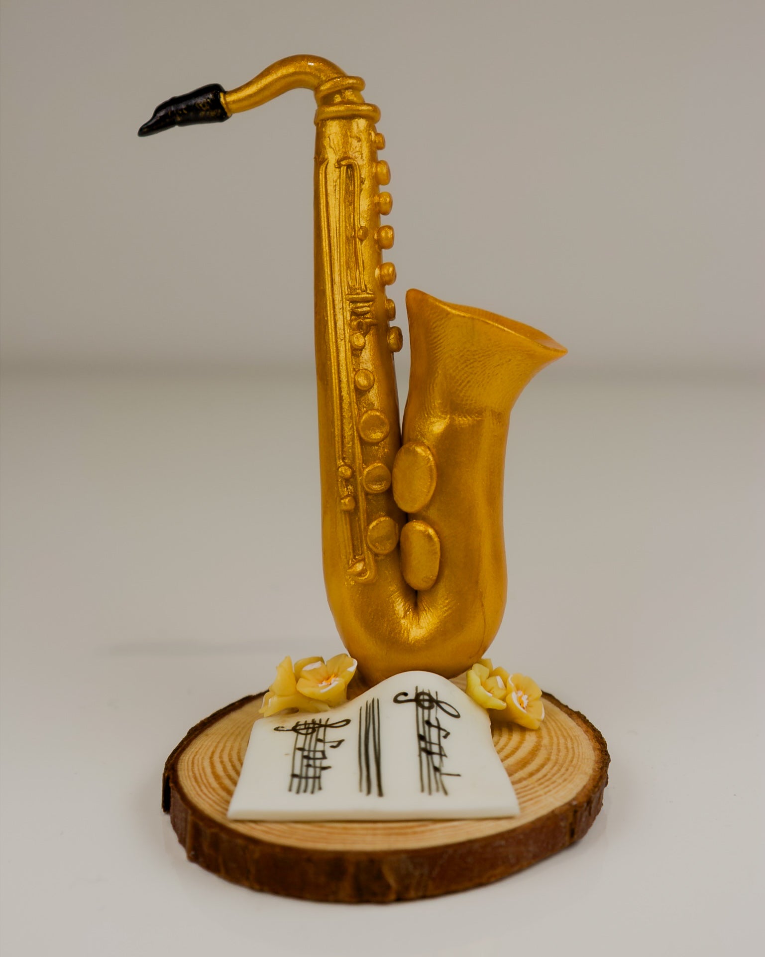 Gold saxophone-shaped object on a wooden base with musical notes