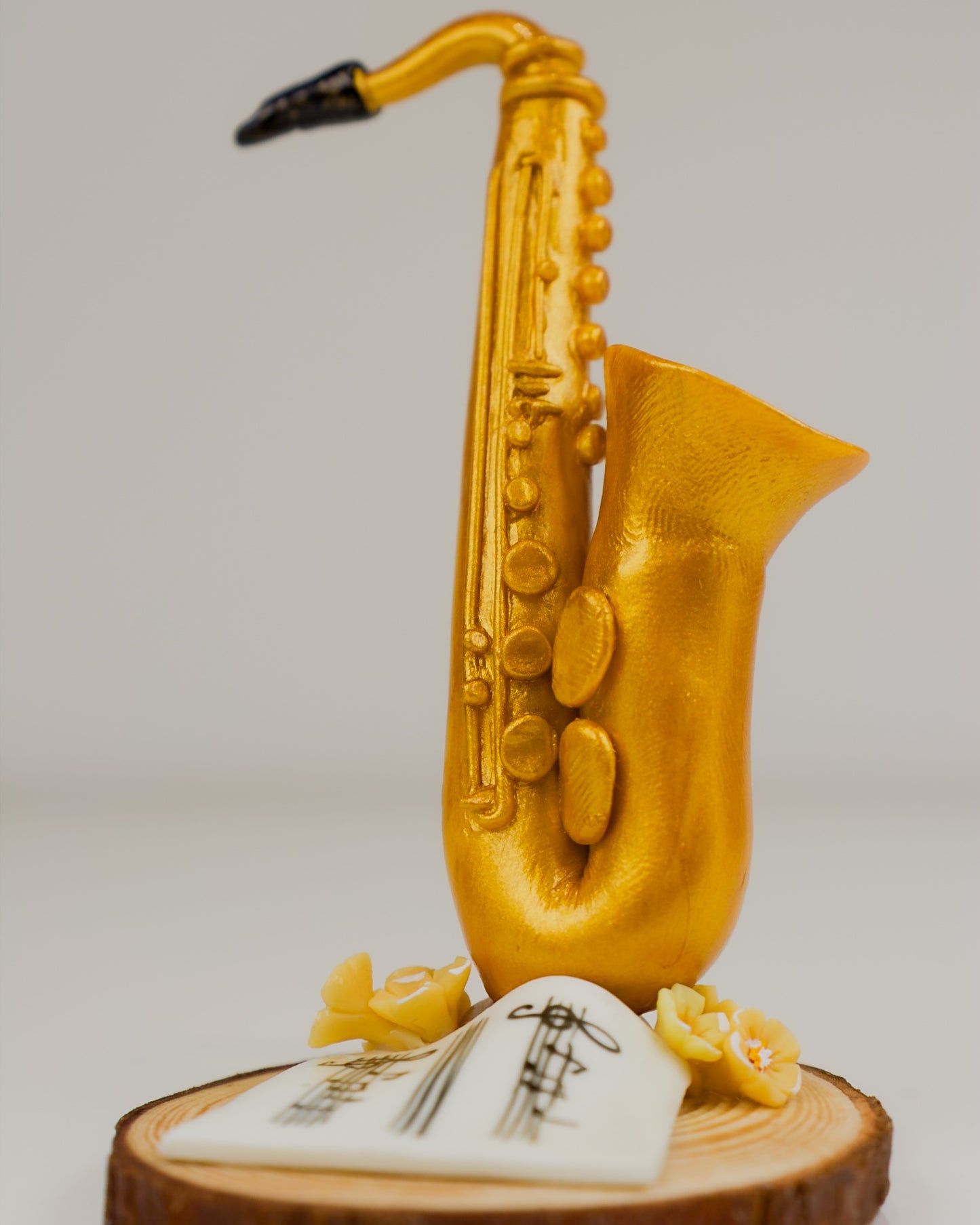 Gold saxophone sculpture on a wooden base with a white platform